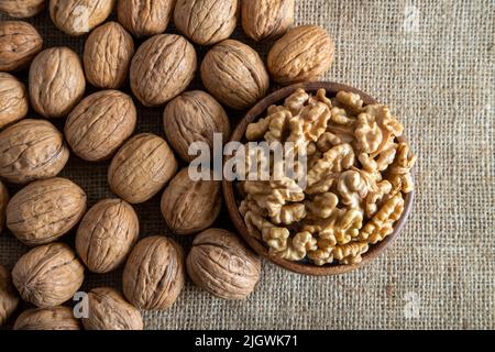 Peeled walnuts and whole walnuts on burlap sack background Stock Photo