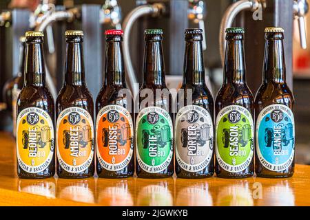 The seven standard beers of Brasserie des Trois Becs stand in a row on the counter in Gigors-et-Lozeron, Drôme, France: Blonde, Ambrée, Rousse, Ortie, Porter, Season and Blanche, all organic-certified. Agricultural scientist Emmanuel Feraa founded the organic brewery in 2015. It grows much of its own hops and barley on site. Stock Photo
