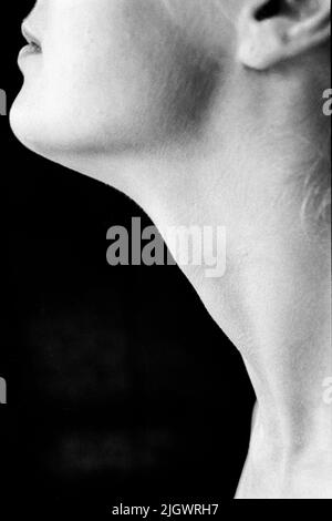 Tilburg, Netherlands. Detail portrait of a young woman's neck, side view en profile, against a black background cloth. Shot on Analog Black & White Film, 1994.