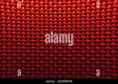 Texture of artificial industrial fabric of red color with a smooth black gradient, forming an interlacing of small squares, wallpaper Stock Photo