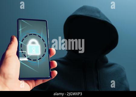 man in a hood Hacker, smartphone with a lock Stock Photo