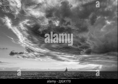 A Storm Is Looming Overhead As A Small Boat Moves Along The Ocean Horizon Black And White Stock Photo