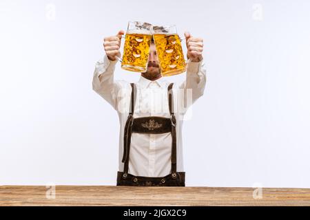 Portrait of Oktoberfest young emotional man in hat, wearing the traditional Bavarian clothes, holding beer mug. Alcohol, traditions, holidays Stock Photo