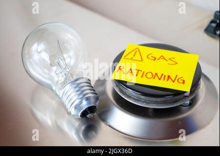 Gas stove, with yellow note next to it with text 'gas rationing' and light bulb off. Rationing and insufficiency in gas flows. Energy crisis. Stock Photo