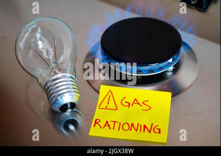 Gas stove, with yellow note next to it with text 'gas rationing' and light bulb off. Rationing and insufficiency in gas flows. Energy crisis. Stock Photo
