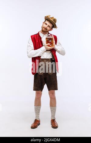 Young handsome man in hat, wearing fest traditional Bavarian or German costume with big beer glass. Alcohol, traditions, holidays, Oktoberfest concept Stock Photo