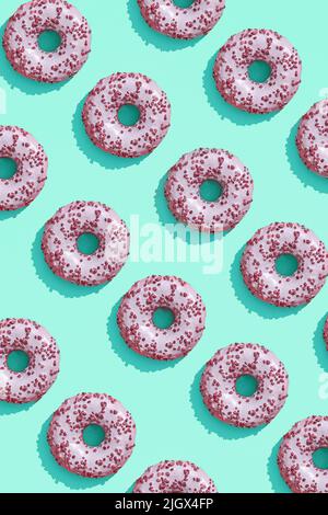 Food design with tasty pink glazed donut on aquamarine green-blue pastel background top view pattern Stock Photo