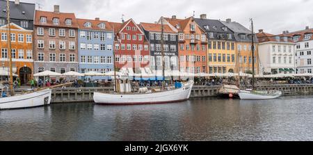 Copenhagen, 2022 june 14 , bright cloudy light on old boats moored in front of picturesque colorful buildings at Nyhavn canal embankment, shot on 2022 Stock Photo