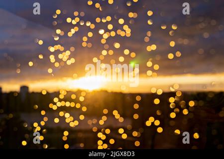 Defocused rain drops on glass window during sunset, blurred background Stock Photo