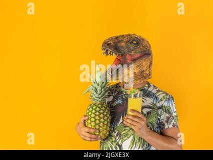 Man wearing dinosaur animal head mask holding pineapple fruit and drinking cocktail or juice .Surreal party , person in party concept Stock Photo
