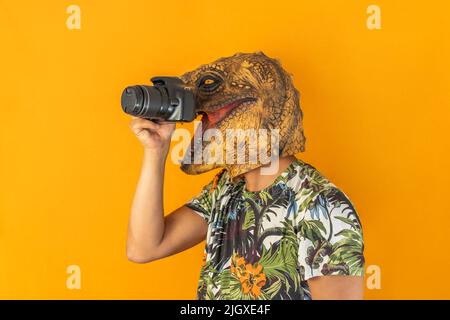 Man taking picture with professional camera wearing animal head mask isolated on yellow background Stock Photo