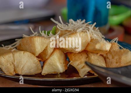 Fried Cassava with cheese sprinkles served on a black ceramic plate, a snack for lunch Stock Photo