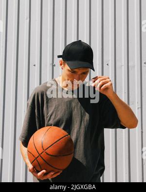 stylish guy in dark clothes and a black cap with a basketball Stock Photo