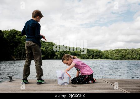 brother and sister crabbing together on a dock in the countryside Stock Photo