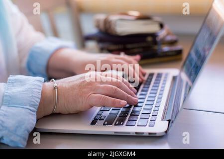 Close-up of white woman's hands typing on laptop Stock Photo