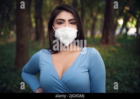 Young latin female in the park with face mask Stock Photo