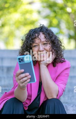 cosmopolitan woman making a video call from her smartphone Stock Photo