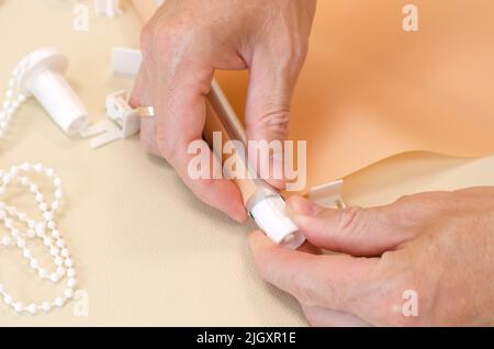 Male hands are assembling roller blinds, close-up. Assembly of roller blinds Stock Photo