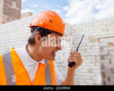 Angry foreman or construction worker speaks on the radio Stock Photo