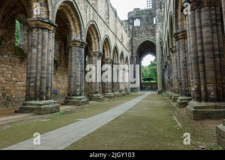 View up the nave towards the altar of Kirkstall Abbey, a ruined Cistercian monastery in Kirkstall, north-west of Leeds, West Yorkshire, England. Stock Photo