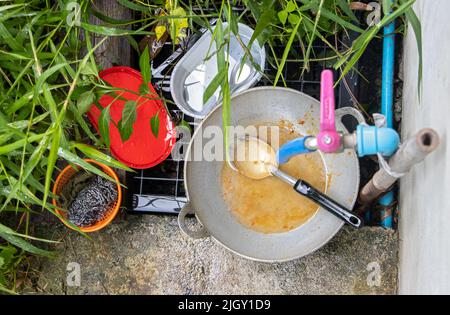 An unwashed dishes under the pipe with tap in the rural backyard Stock Photo