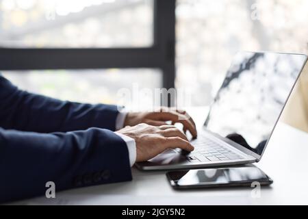 Closeup Shot Of Hands Of Unrecognizable Businessman In Suit Working On Laptop Stock Photo