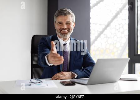Smiling Middle Aged Businessman Extending Hand For Handshake At Camera Stock Photo