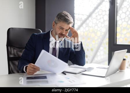 Busy Middle Aged Entrepreneur Working With Documents In Modern Office Stock Photo