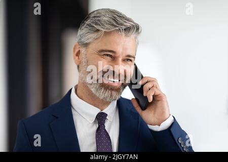 Closeup Portrait Of Handsome Mature Businessman Talking On Mobile Phone Indoors Stock Photo