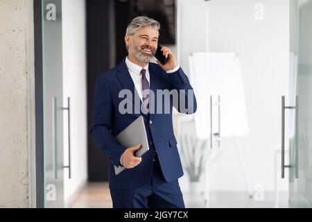 Portrait Of Happy Middle Aged Businessman In Suit Walking Out Of Office Stock Photo