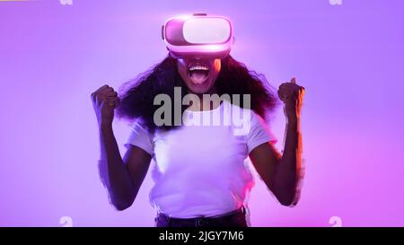 Black lady in VR glasses exploring cyberspace, shouting in excitement Stock Photo