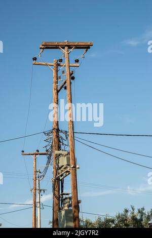 External transformer on wooden poles connected into electric energy on blue sky background Stock Photo