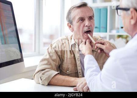 Doctor Using Tongue Depressor Photograph by Science Photo Library