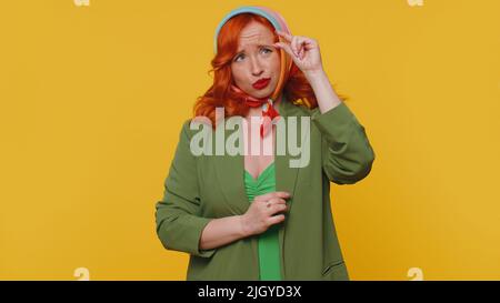 Need some more please give me. Woman showing a little bit gesture with sceptic smile, showing minimum sign, measuring small size asking for help. Ginger girl isolated alone on yellow studio background Stock Photo