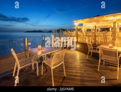 Beautiful cafe on sea coast at night in summer. Chairs and tables Stock Photo