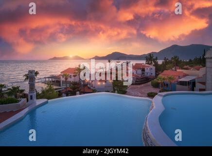 Beautiful swimming pool, sky with pink clouds at colorful sunset Stock Photo