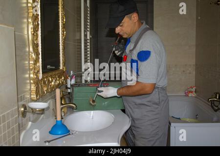 Image of a smiling plumber who unclogged a clogged sink with a probe. Do-it-yourself work Stock Photo