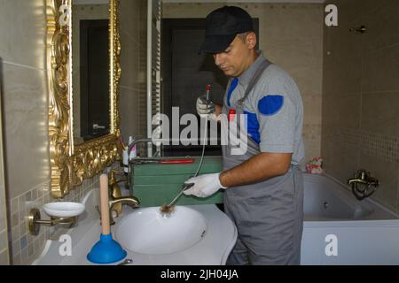 Image of a smiling plumber who unclogged a clogged sink with a probe. Do-it-yourself work Stock Photo