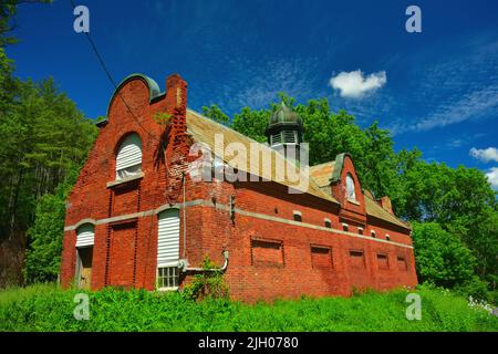 A low angle shot of an orange house made of bricks surrounded with lush greenery Stock Photo