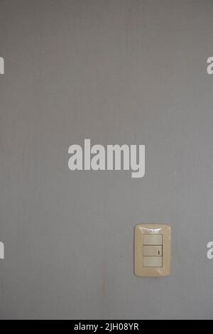 Title: White light switch on plain gray wall background Stock Photo