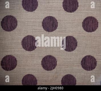 Purple polka dot pattern on beige textured fabric background Stock Photo