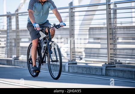 A man on a bike pedals a bicycle on a dedicated path for cyclists on the Tilikum Crossing bridge preferring an active healthy lifestyle using cycling