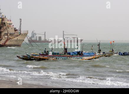 PORTUGUESE TOWN, BANJUL, THE GAMBIA - FEBRUARY 10, 2022 fishing boats and container ship arriving Stock Photo