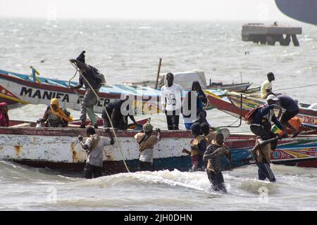 PORTUGUESE TOWN, BANJUL, THE GAMBIA - FEBRUARY 10, 2022 porters carrying passengers on their shoulders from the boats Stock Photo