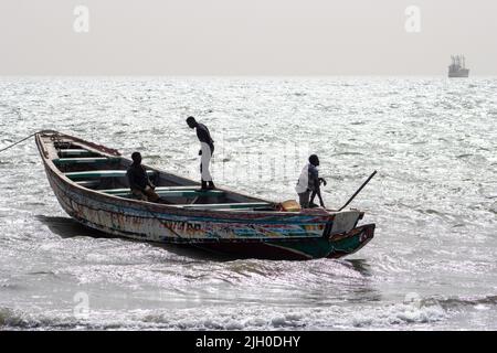 PORTUGUESE TOWN, BANJUL, THE GAMBIA - FEBRUARY 10, 2022 silhouette of local fishing boats and men working on the boats Stock Photo