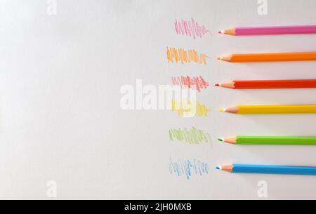 Various colored pencils on white striped paper. Top view. Horizontal composition. Stock Photo