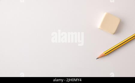 Teaching and education background with pencil and eraser on white paper. Top view. Stock Photo