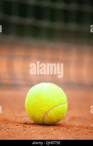 Yellow tennis ball lies on the clay court close up. Stock Photo
