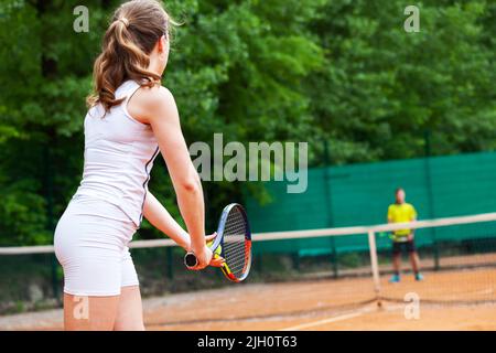 Young beautiful female tennis player serving. Stock Photo