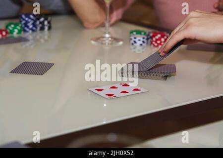 Women's hands take cards. Concept of playing poker on the table with chips and cards. Gambling concept. Enjoying the moment, digital detox with friends. Selective focus. Stock Photo